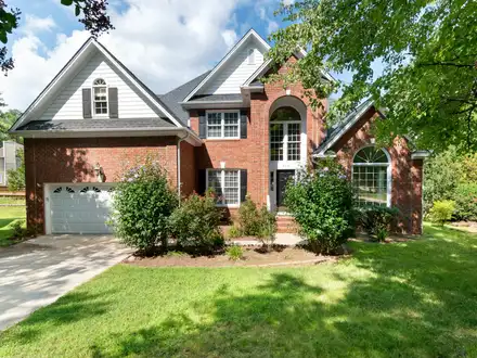 Two-story brown brick home with landscaped front lawn